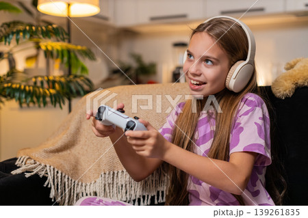 Teenager girl plays console game with joystick focused strong reaction enjoys free time after school 139261835