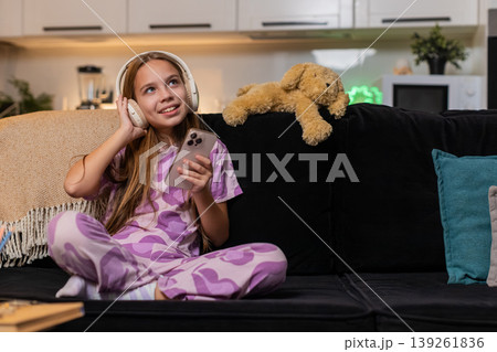Teenager girl enjoys music with wireless headphones from smartphone smiles moves dances happy rhythm 139261836