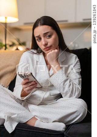 Young woman bored scrolling smartphone news tired stressed unmotivated burnout sighs looks evening Young woman bored scrolling smartphone news tired stressed unmotivated burnout sighs looks evening 139261843