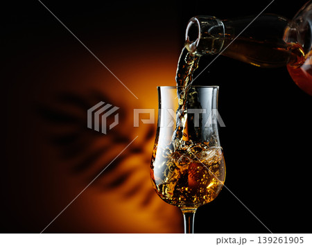 Rum being poured from a bottle into a glass. 139261905