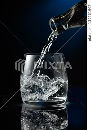 Crystal clear vodka being poured over ice in a glass. Crystal clear vodka being poured over ice in a glass. 139261907
