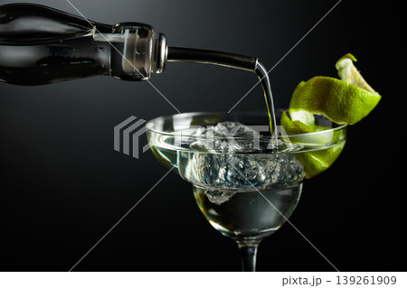 Vodka or gin is poured into a glass with ice. Vodka or gin is poured into a glass with ice. 139261909