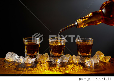 Whiskey pours from bottle to glass. 139261911