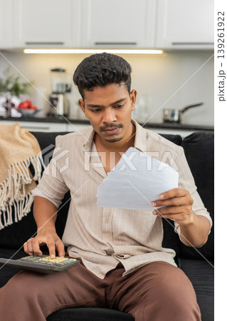 Indian man plans utility budget uses calculator holds bills squints and marks priorities for month Indian man plans utility budget uses calculator holds bills squints and marks priorities for month 139261922