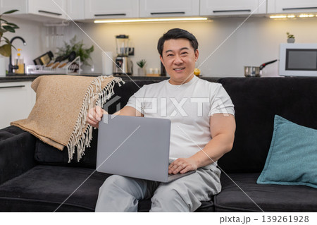 Asian man launches laptop for work logs in types quickly smiles with confidence ready to start tasks 139261928