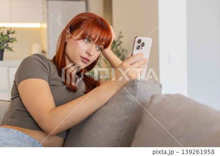 Young woman tires of endless news feed on smartphone bored annoyed low energy and mental drain mood 139261958