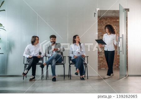 A woman walked out, calling someone. People near the wall, waiting for a job interview, potential workers 139262065