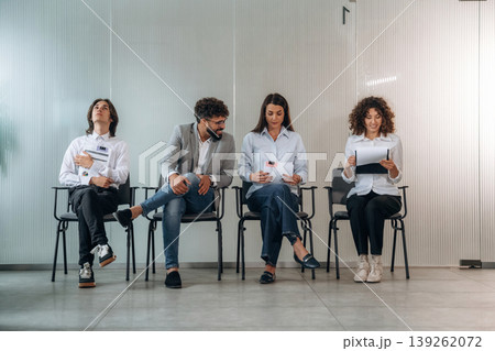 Excited, sitting. People near the wall, waiting for a job interview, potential workers Excited, sitting. People near the wall, waiting for a job interview, potential workers 139262072
