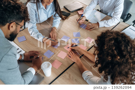 Brainstorming process. Office workers are by the table with paper stickers Brainstorming process. Office workers are by the table with paper stickers 139262094