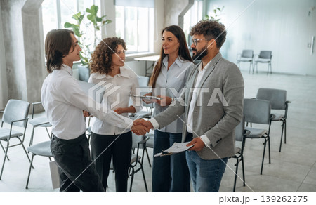Met with a partner, doing handshake. Group of people are working in the office together as a team 139262275