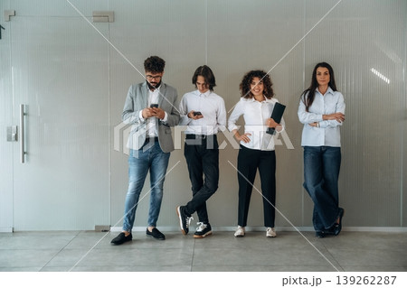 Just bored. Front view of four office workers that are standing indoors and waiting Just bored. Front view of four office workers that are standing indoors and waiting 139262287