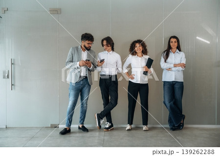 Just bored. Front view of four office workers that are standing indoors and waiting 139262288