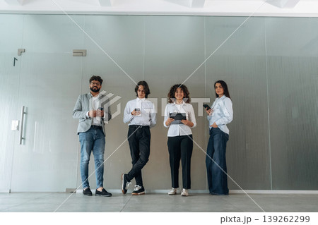 Front view of four office workers that are standing indoors and waiting 139262299