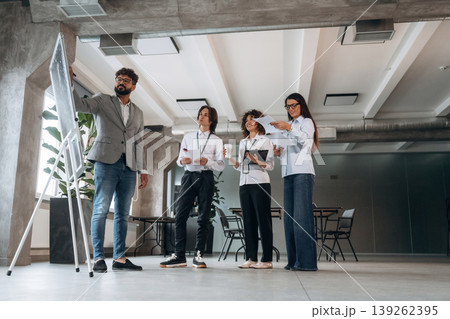 Writing data on the board, explaining stuff. Four office workers are together, employees at work 139262395