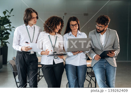 Holding laptop and standing. Group of people are working in the office together as a team 139262409