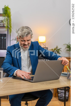 Middle-aged businessman fumes at laptop frozen error closes lid sighs disappointed frustration shows 139262582