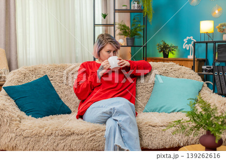 Woman enjoying drinking coffee sitting comfortably on sofa relaxed satisfied calm leisure expression 139262616