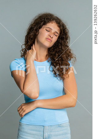Woman rubbing painful neck suffering discomfort muscle tension stress tired exhausted expression 139262632