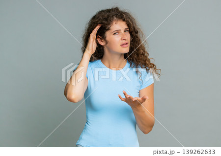 Woman holding hand near ear gesture listening carefully indicating cannot hear confused reaction 139262633