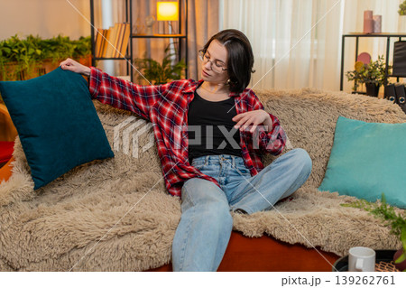 Smiling woman arranging decorative pillows at home, satisfaction while admiring clean living space 139262761