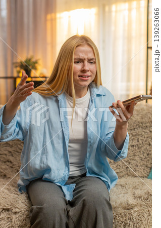 Young woman on loudspeaker call, emotional argument escalates, frustrated end tense home sofa moment 139263066