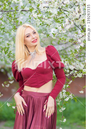 Smiling Blonde Woman In Burgundy Outfit Near Blossoms Smiling Blonde Woman In Burgundy Outfit Near Blossoms 139263535