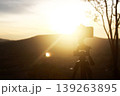 Sunset Serenity: A lone tripod stands tall, framing a breathtaking sunset with golden hues. Capturing a moment of solitude. 139263895