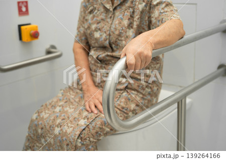 Asian elderly woman patient use toilet support rail in bathroom. 139264166