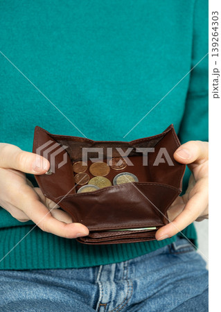 High angle shot of a person holding an open brown leather wallet filled with various euro coins. High angle shot of a person holding an open brown leather wallet filled with various euro coins. 139264303