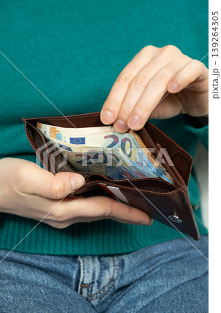 Hands holding a leather purse with visible paper money. 139264305