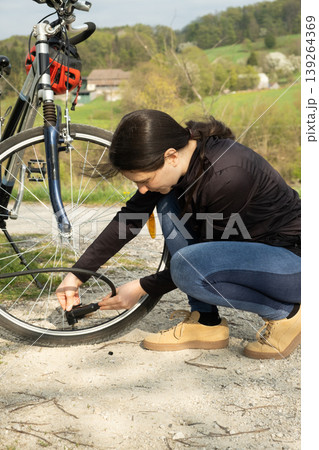 Woman connecting a pump to a bicycle tire at a repair station. Woman connecting a pump to a bicycle tire at a repair station. 139264369