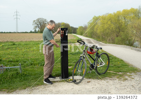 Man using a public bike pump station to inflate a tire. Man using a public bike pump station to inflate a tire. 139264372