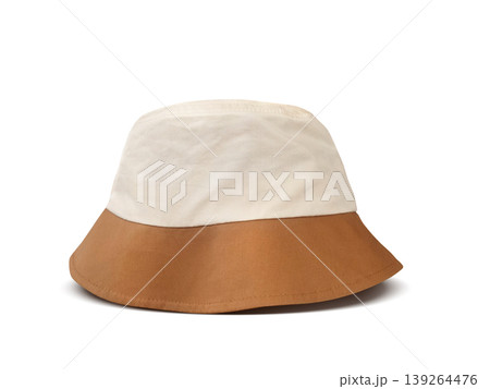 A white and brown bucket hat is placed on a white floor. A white and brown bucket hat is placed on a white floor. 139264476