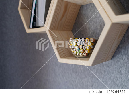 A young woman places a glass bowl filled with used batteries onto a wooden shelf for future disposal. This process demonstrates conscious household waste sorting and care for the environment. A young woman places a glass bowl filled with used batteries onto a wooden shelf for future disposal. This process demonstrates conscious household waste sorting and care for the environment. 139264731