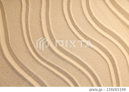 Waves of sand form lines on a sunny beach shore 139265199