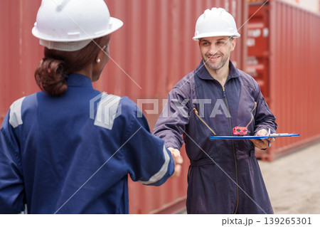 Smiling mid-adult Caucasian male and Black female logistics professionals shaking hands at Asian shipping port. Smiling mid-adult Caucasian male and Black female logistics professionals shaking hands at Asian shipping port. 139265301