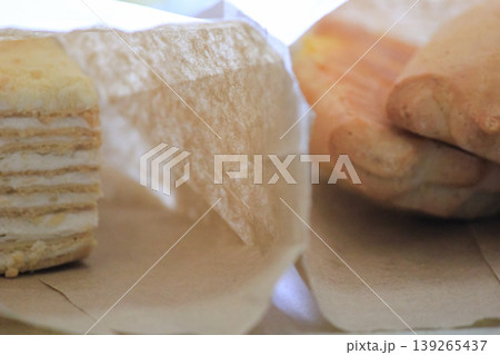 Assorted sweet treats including layered cake and cookies in rustic paper bags for takeaway closeup 139265437