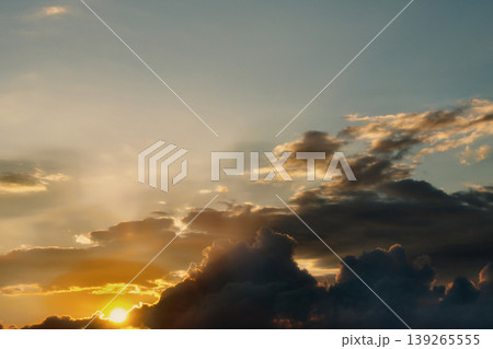 Dramatic Golden Sunset Clouds on Dark Blue Sky. Breathtaking high-contrast sky at sunset. Golden light illuminates dark storm clouds against a deep blue dusk sky. 139265555