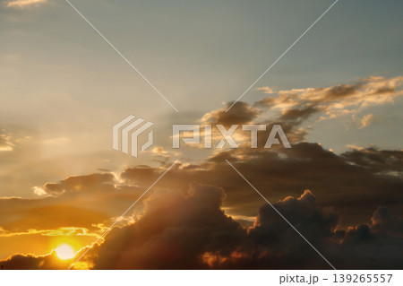 Dramatic Golden Sunset Clouds on Dark Blue Sky. Breathtaking high-contrast sky at sunset. Golden light illuminates dark storm clouds against a deep blue dusk sky. 139265557
