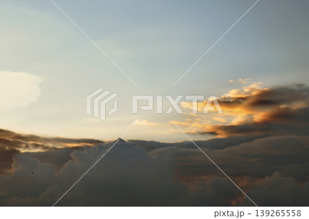 Dramatic Golden Sunset Clouds on Dark Blue Sky. Breathtaking high-contrast sky at sunset. Golden light illuminates dark storm clouds against a deep blue dusk sky. 139265558