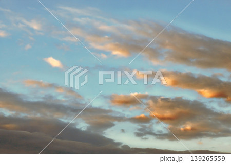 Dramatic Golden Sunset Clouds on Dark Blue Sky. Breathtaking high-contrast sky at sunset. Golden light illuminates dark storm clouds against a deep blue dusk sky. 139265559