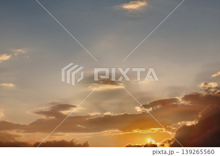 Dramatic Golden Sunset Clouds on Dark Blue Sky. Breathtaking high-contrast sky at sunset. Golden light illuminates dark storm clouds against a deep blue dusk sky. 139265560