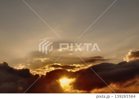 Dramatic Golden Sunset Clouds on Dark Blue Sky. Breathtaking high-contrast sky at sunset. Golden light illuminates dark storm clouds against a deep blue dusk sky. 139265564