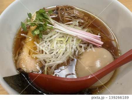透き通ったスープの醤油ラーメンと味玉 白髪ねぎとチャーシューが乗った上品な盛り付けの麺料理のアップ 139266189