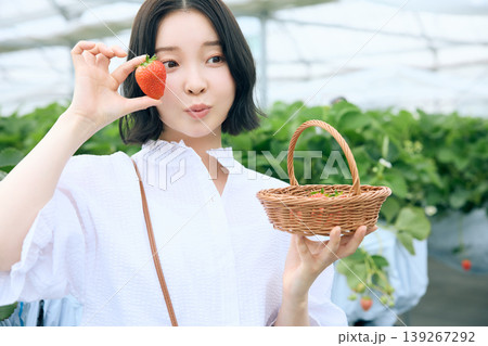 いちご狩りを楽しむ若い女性・ビニールハウスで摘みたての苺を持ち微笑む日本人女性 139267292
