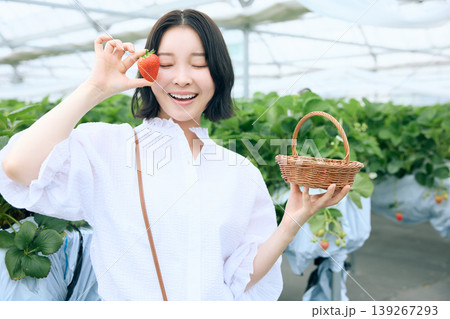 いちご狩りを楽しむ笑顔の若い女性・ビニールハウスで苺を持つ日本人女性のポートレート 139267293