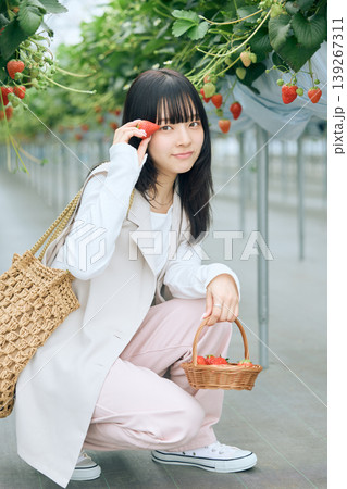 いちご狩りを楽しむ若い女性・ビニールハウスで苺を持って微笑む黒髪の日本人女性 139267311
