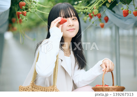 いちご狩りを楽しむ若い女性・ビニールハウスで摘みたてのイチゴを持って微笑む日本人女性 139267313