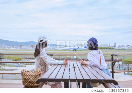 空港の展望デッキで飛行機を眺めながらいちごを食べる若い女性たち・友達同士の休日おでかけ 空港の展望デッキで飛行機を眺めながらいちごを食べる若い女性たち・友達同士の休日おでかけ 139267336