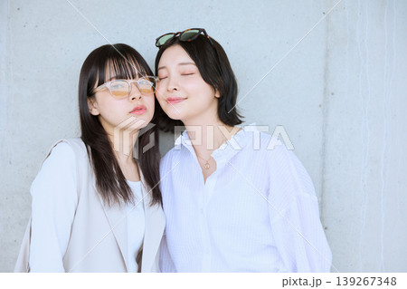 白い服を着た若い女性二人が寄り添い目を閉じて微笑む友情ポートレート・コンクリート壁背景 白い服を着た若い女性二人が寄り添い目を閉じて微笑む友情ポートレート・コンクリート壁背景 139267348